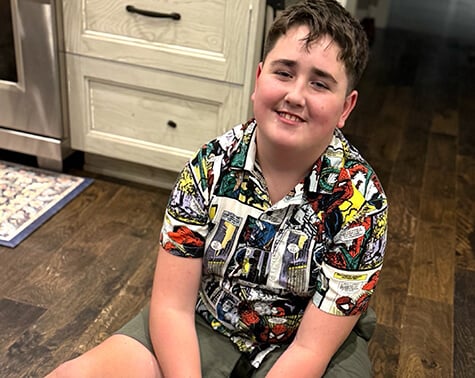 Photo of Ethan sitting on the floor and smiling at the camera